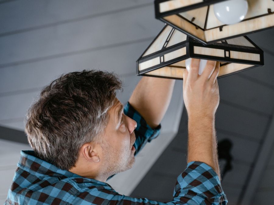 Installation d'un luminaire au plafond par un professionnel.